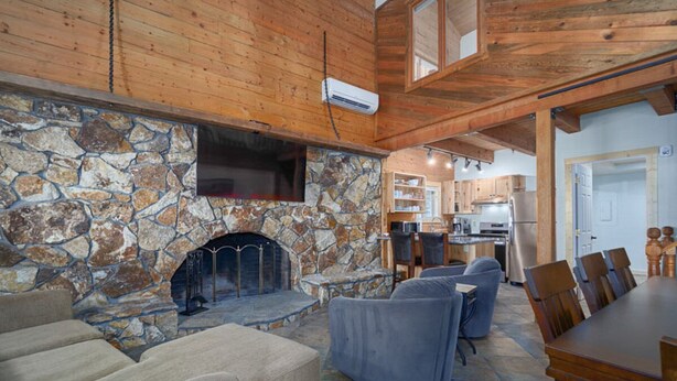 Ein gemütliches Wohnzimmer mit Kamin aus Stein, Holzboden und einem Essbereich mit Holztisch und -stühlen.