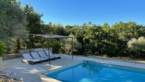 Una piscina con sillas de descanso y una pérgola.