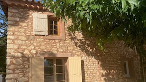 Un edificio de piedra con una puerta de madera y contraventanas.