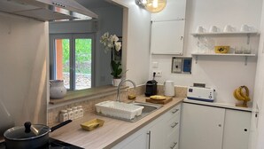 Una cocina moderna con estufa integrada, lavamanos y ventana con vista a zonas verdes.