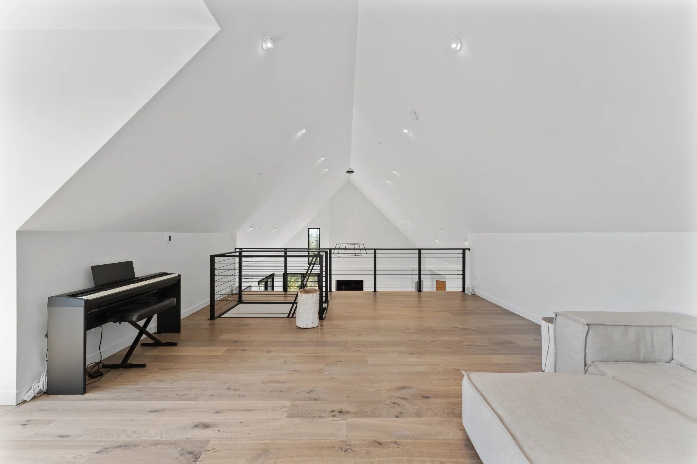 Un loft spacieux avec un piano, un escalier et un canapé.