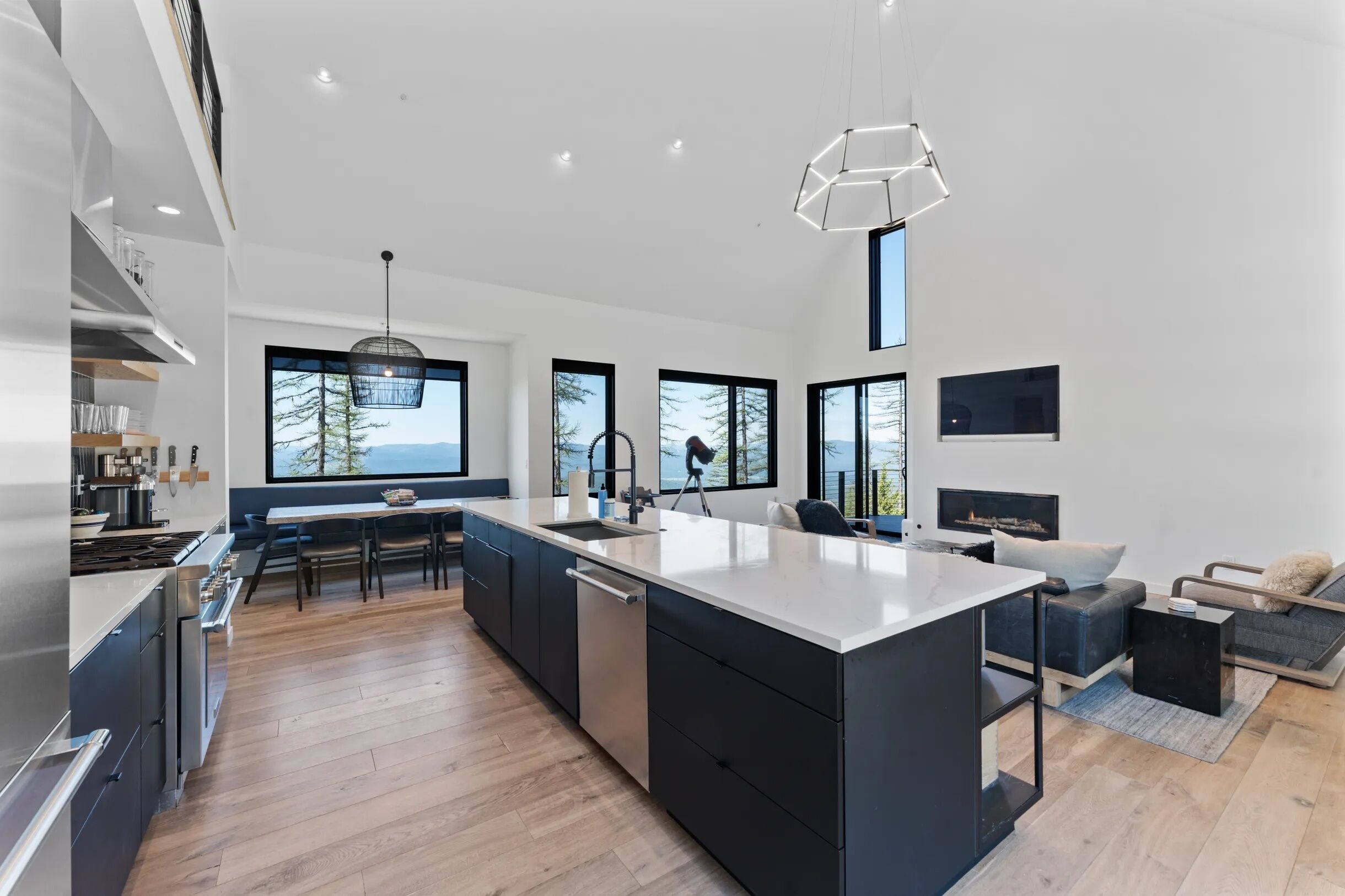 Una cocina moderna con una isla grande, electrodomésticos integrados y amplios ventanales con vistas al exterior.