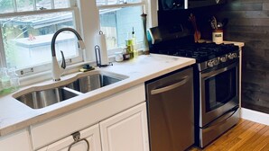 Een moderne keuken met witte kasten, roestvrijstalen apparatuur en een houten vloer.