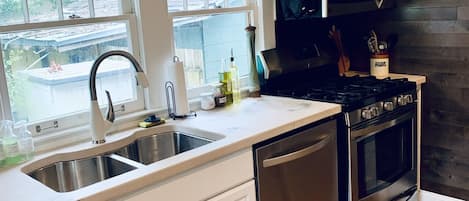 A modern kitchen with white cabinets, stainless steel appliances, and a wooden floor.