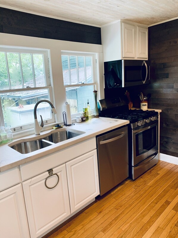A modern kitchen with white cabinets, stainless steel appliances, and a wooden floor. - Pet Friendly 2/1.5 in the Heart of Historic Pensacola (Pensacola)