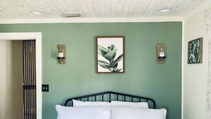 Een slaapkamer met een bed, een groene muur en twee wandlampen.