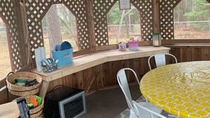 A wooden interior with a round table covered in a yellow tablecloth, white chairs, and a wooden counter with various items. - Lake House 100 yards off snowmobile trail #8.  (Michigamme)