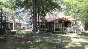 A rustic cabin with a red roof, surrounded by trees and a fenced yard. - Lake House 100 yards off snowmobile trail #8.  (Michigamme)