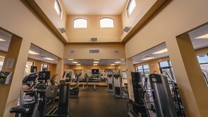 Un gimnasio con cintas de correr, máquinas de pesas y una pantalla de televisión.