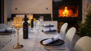 A dining table set for a meal with a fireplace in the background. - Villa Calypso with Pool (Podstrana)