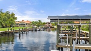 A waterfront property with a dock, a covered boat launch, and a house with a red roof. - Waterfront! Docks available for rent and extra parking lot and ice machine (Homosassa)