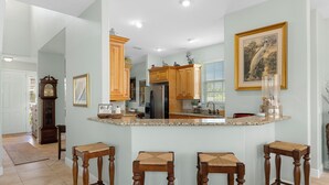 A kitchen with wooden cabinets, a granite countertop, and a bar area with stools. - Waterfront! Docks available for rent and extra parking lot and ice machine (Homosassa)