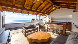 A spacious living area with a wooden ceiling, a large round wooden table, and a view of the ocean. - DREAM CONDO: OCEAN VIEWS & ONLY STEPS FROM THE BEACH (Puerto Vallarta)