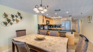 A dining area with a marble table, wicker chairs, and a hanging light fixture.