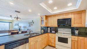 A modern kitchen with wooden cabinets, a black microwave, a white stove, and a dishwasher.
