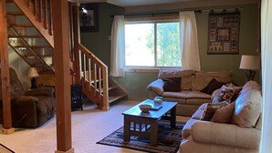 A cozy living room with a staircase, a sofa, a coffee table, and a window with curtains. - Cozy Cabin in the national forest  (Pagosa Springs)
