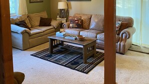 A cozy living room with two leather sofas, a wooden coffee table, and a patterned rug. - Cozy Cabin in the national forest  (Pagosa Springs)