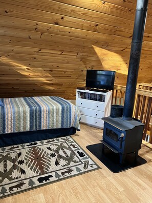 Une chambre confortable dans un chalet, avec un lit, une commode et un poêle à bois.