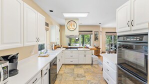 A modern kitchen with white cabinetry, a large island, and a built-in oven.