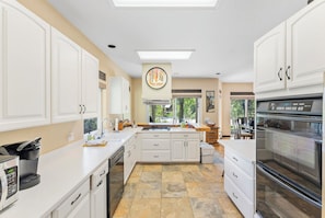 A modern kitchen with white cabinetry, a large island, and a built-in oven.