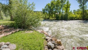 A river with a rocky bank and trees in the background.