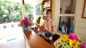 Una recepción con mostrador de madera, un jarrón de flores y un tablón de anuncios al fondo.