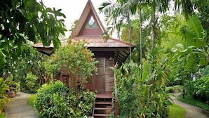 A small, triangular-roofed structure surrounded by lush greenery and a concrete pathway. - Baan Duangkaew (Hua Hin)