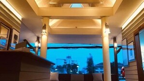 A modern interior with a wooden ceiling, hanging spherical lights, and a seating area with a view of the outside. - Baan Duangkaew (Hua Hin)