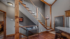 Una escalera con barandillas de madera y una barandilla metálica, que conduce a un rellano con una pequeña mesa y un marco de fotos.