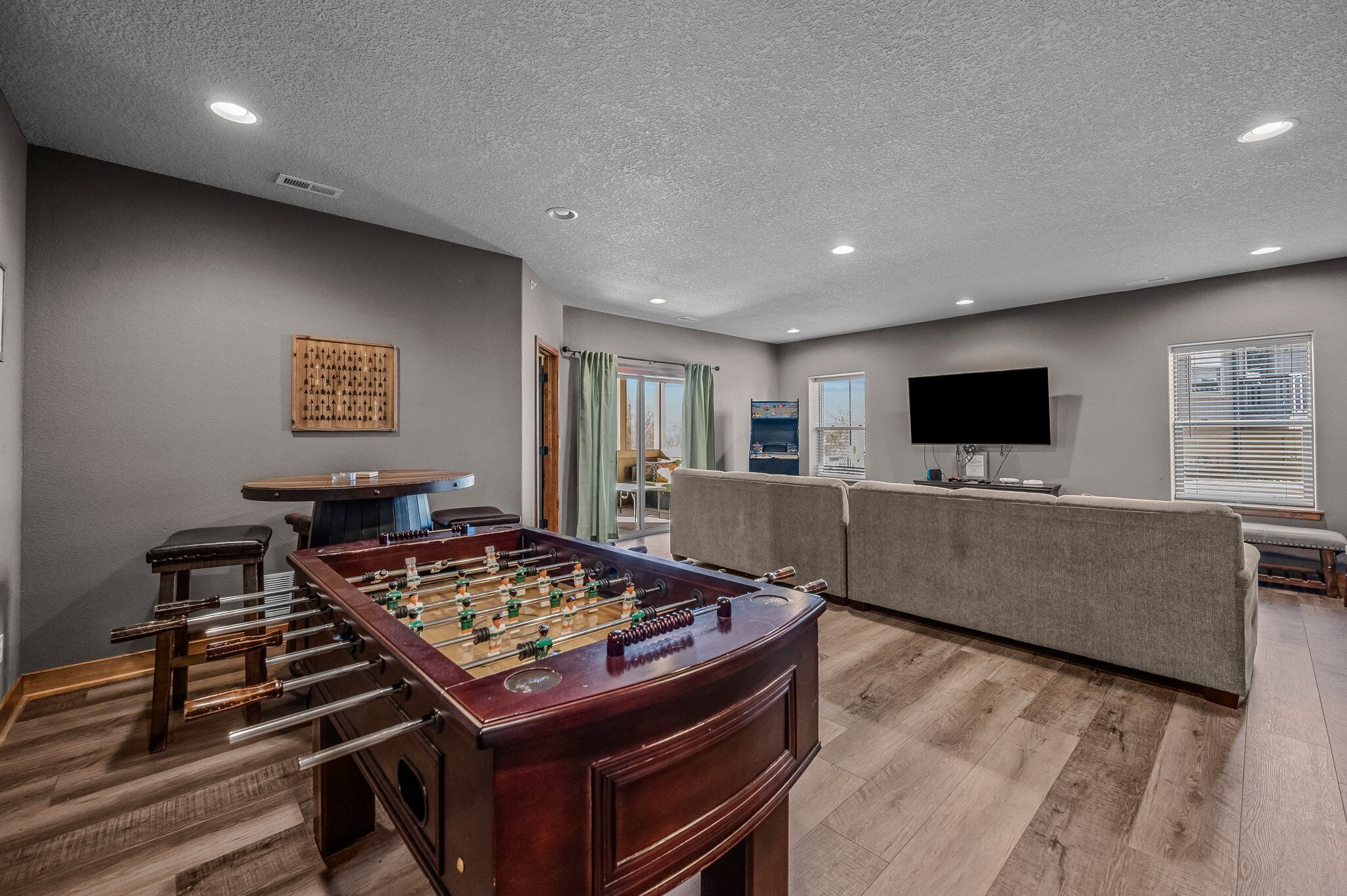 A spacious living room with a foosball table, a sofa, and a flat-screen TV.