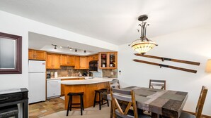 A kitchen with wooden cabinets, a white refrigerator, a built-in oven, and a bar area with stools. - Family Friendly Condo- Walk to Main Street and Town Lift (Park City)