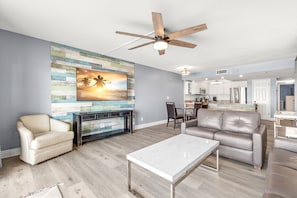 Relax in this stylish living room with a flat-screen TV, comfortable seating area, and modern kitchen.