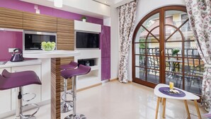 Une cuisine moderne équipée d’un téléviseur, de tabourets de bar violets et d’un coin repas avec une table et des chaises.