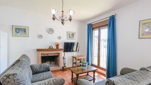 A living room with a fireplace, two sofas, a coffee table, and a TV mounted on the wall. - Casas Villanueva - Casa 2 Conil de la Frontera by Ruralidays (Cádiz)