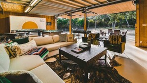 Un espacio interior acogedor con sofá, mesa de centro, sillas, una mesa de billar y vistas al exterior.