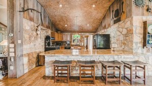 Una cocina rústica con pared de piedra, taburetes de madera y una isla grande.