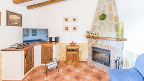 Una sala de estar con televisor, armarios de madera, chimenea de piedra y piso con diseño.
