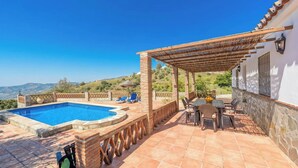 Un espace piscine aménagé sur le toit, avec une pergola, des sièges et une vue sur le paysage.