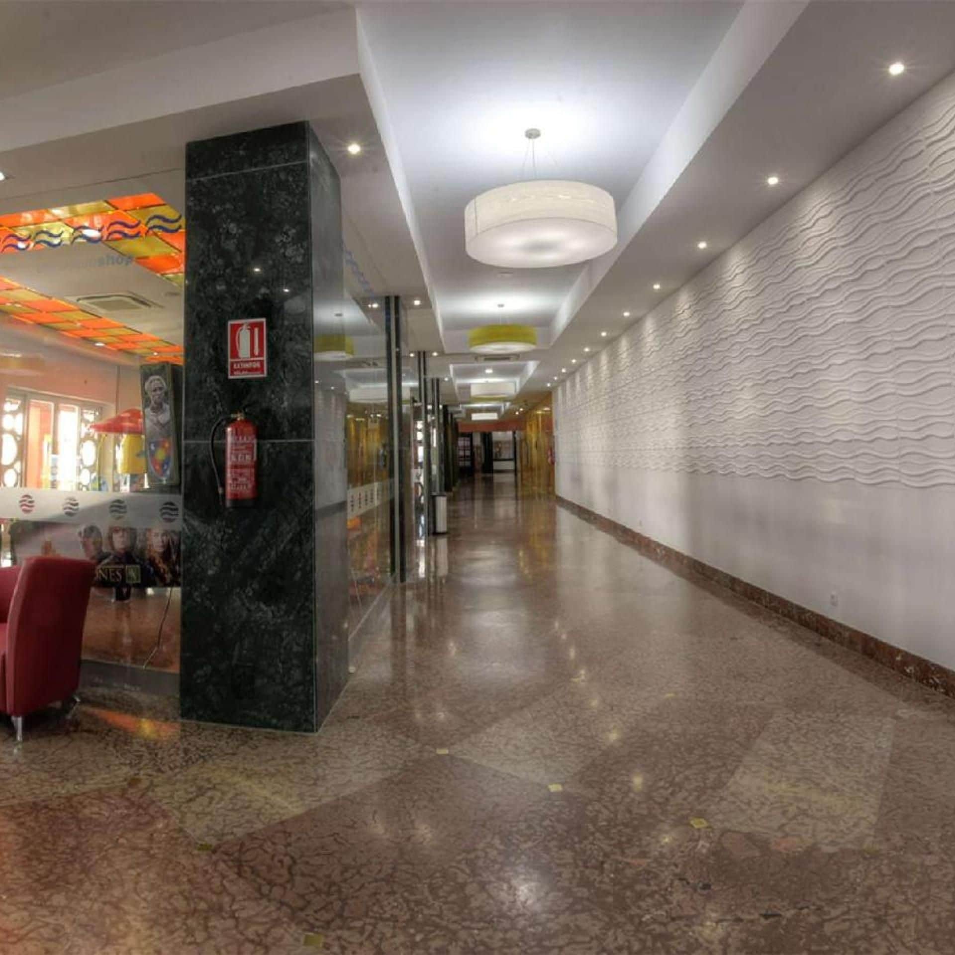 A hotel corridor with a marble column, a fire extinguisher, and a patterned wall.