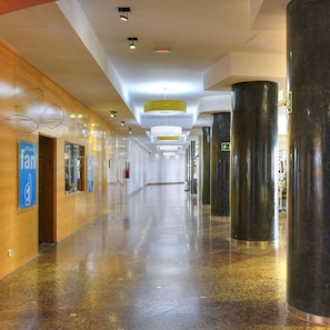 A long, well-lit corridor with a polished floor, a blue sign indicating a fan, and a green emergency exit sign. - Hotel Spa Entremares (Cartagena)