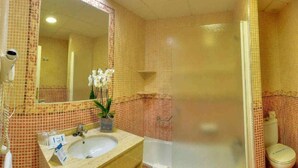A bathroom with a sink, mirror, shower, and toilet. - Hotel Spa Entremares (Cartagena)