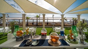 A table set for breakfast with a view of the ocean, under a large canopy. - Hotel Spa Entremares (Cartagena)