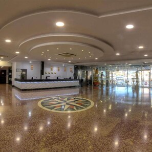 A spacious lobby with a reception desk, a decorative floor pattern, and a ceiling with recessed lighting. - Hotel Spa Entremares (Cartagena)