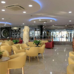 Um saguão de hotel com mesas redondas, cadeiras e uma estátua.