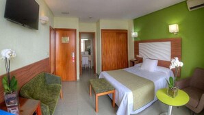 A hotel room with a bed, a desk, a chair, a small table, and a TV. - Hotel Spa Entremares (Cartagena)