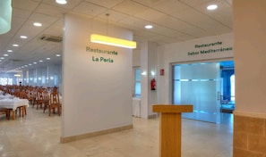 A restaurant interior with tables and chairs, a wooden podium, and signage for 'Restaurante La Perla' and 'Restaurante Sabor Mediterráneo'. - Hotel Spa Entremares (Cartagena)