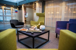 A modern lounge area with a glass door entrance, a table with a plate of food, and two chairs. - Park Inn By Radisson Reykjavik Keflavik Airport (Reykjanesbær)
