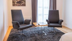 A modern room with two grey armchairs, a small wooden table, and a black shag rug. - Park Inn By Radisson Reykjavik Keflavik Airport (Reykjanesbær)