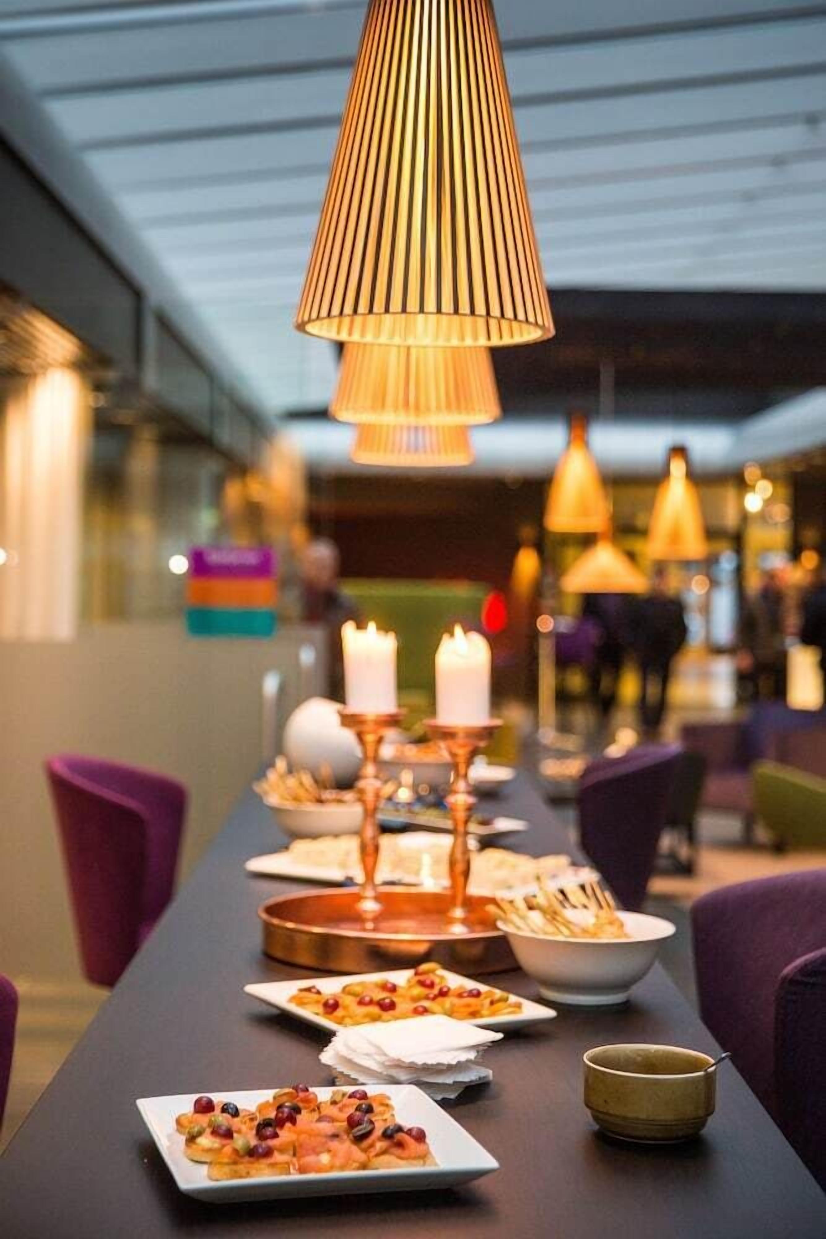A dining area with a long table set for a meal, featuring candles and a variety of dishes.