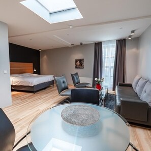 Una habitación de hotel moderna con una cama, un sofá, una mesa de vidrio y un tragaluz.